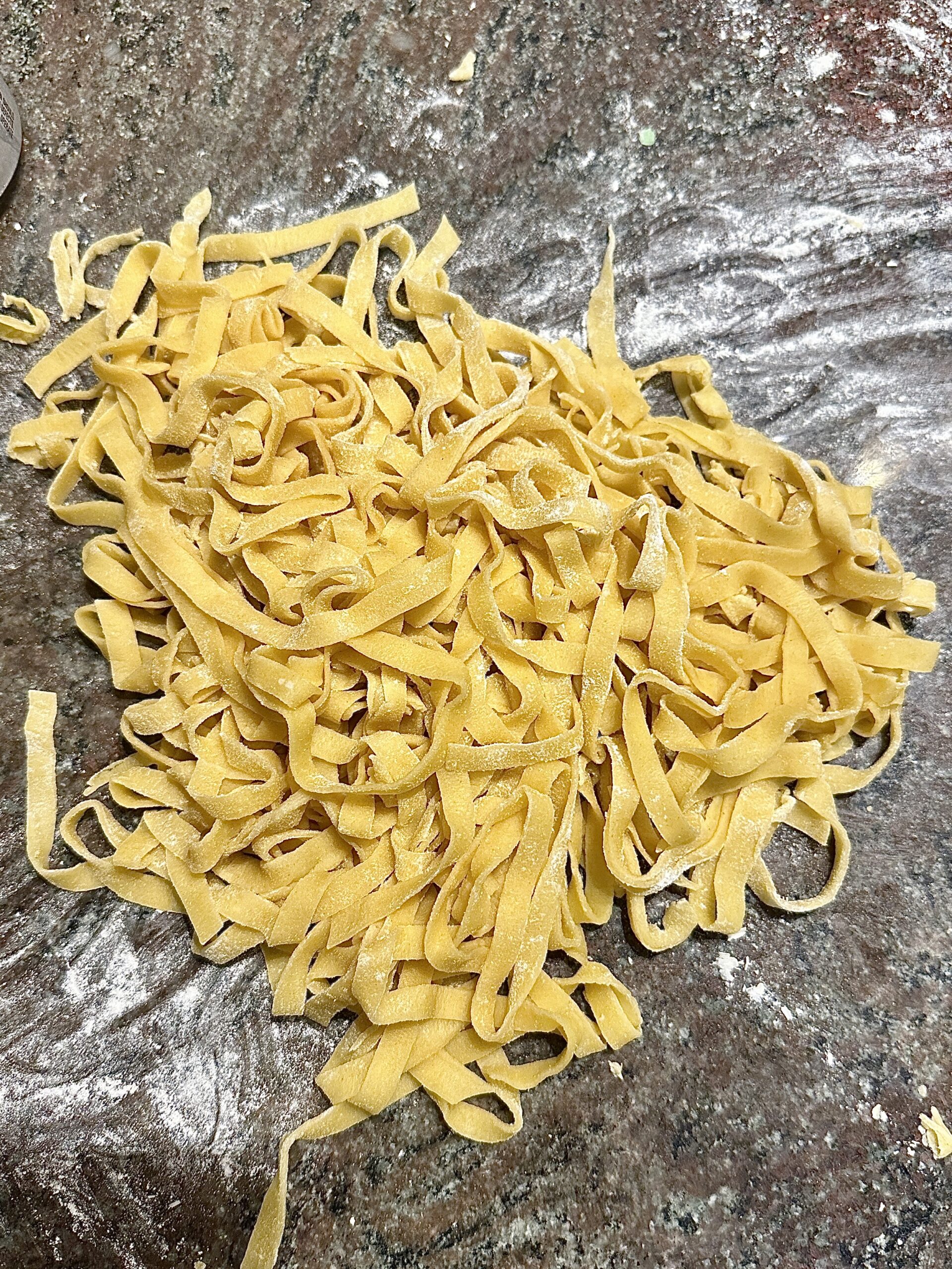 Uncooked fresh handmade pasta laid out on a kitchen counter, ready for cooking.